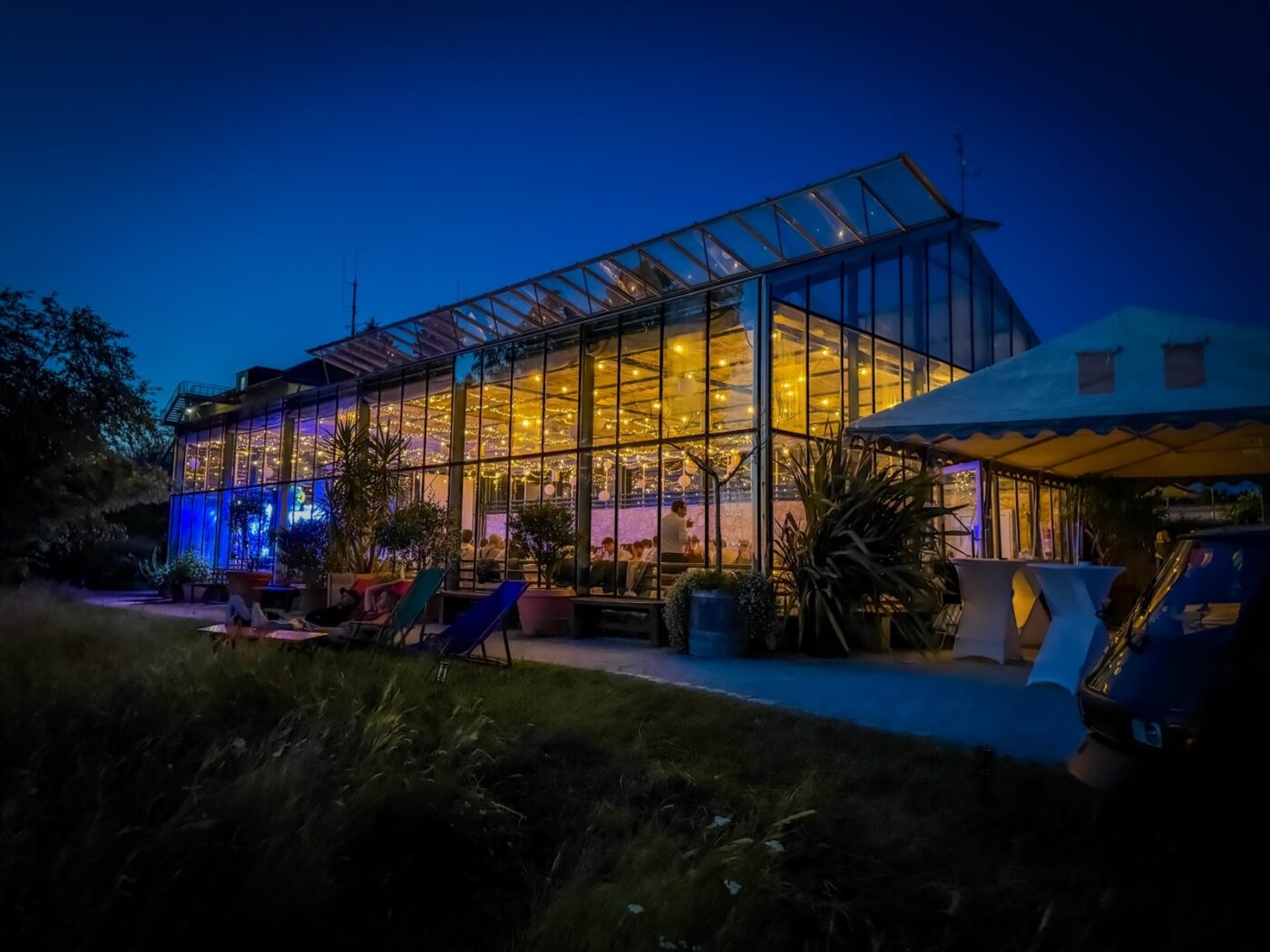 Beleuchtetes Glashaus bei einer Hochzeitsfeier am Abend